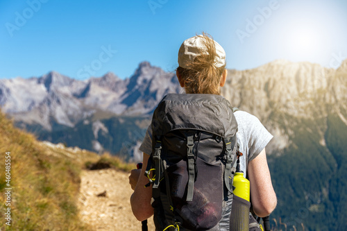 Woman hiking a trail in the Italian alps at the end of summer or fall. Dolomite peaks of Rosengarten - Catinaccio are visible in the background. Carezza, Val d'Ega - Trentino, Italy photo