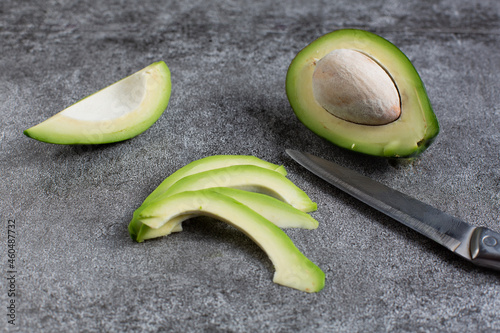 green avocado lie on an artificial stone board. diet food. green vegetable.