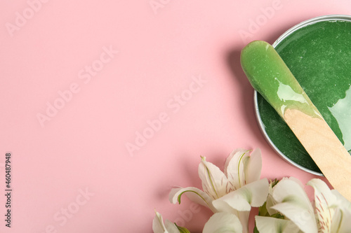 Fototapeta Naklejka Na Ścianę i Meble -  Wooden spatula, hot depilatory wax and flowers on light pink background, flat lay. Space for text