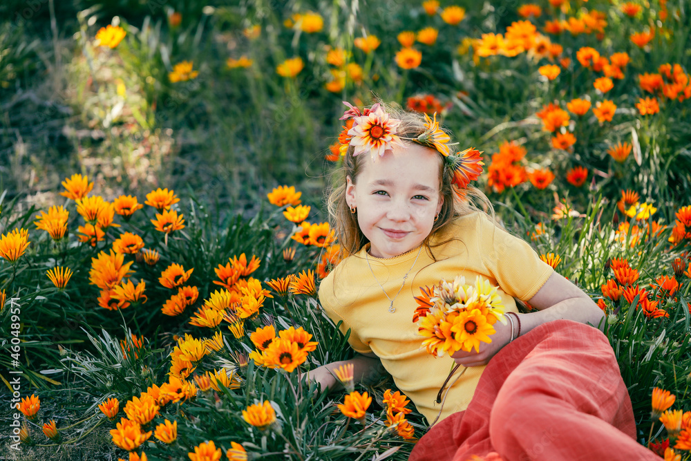 Portrait of pretty girl sitting in field with vibrant orange and yellow wildflowers Portrait of pretty girl sitting in field with vibrant orange and yellow wildflowers