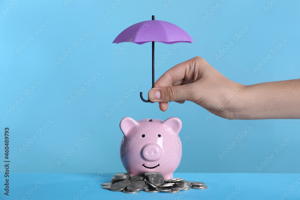Woman Holding Small Umbrella Over Piggy Bank With Coins On Light Blue Background Closeup Stock 写真 Adobe Stock