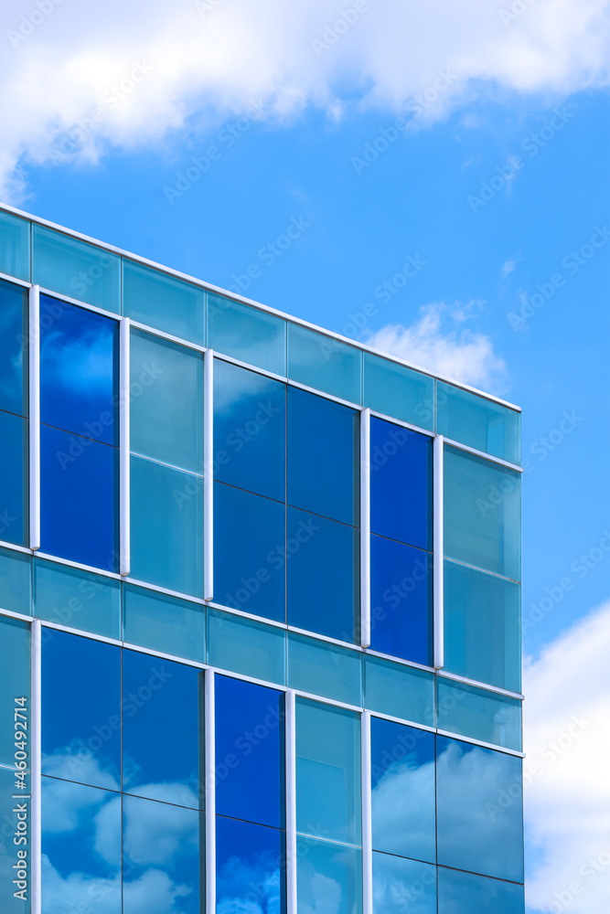 Stunning reflection on surface of modern glass office building against white cloud on blue sky background in vertical frame Stunning reflection on surface of modern glass office building against white cloud on blue sky background in vertical frame