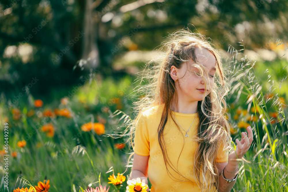 Portrait of pretty girl sitting in field with vibrant orange and yellow wildflowers Portrait of pretty girl sitting in field with vibrant orange and yellow wildflowers
