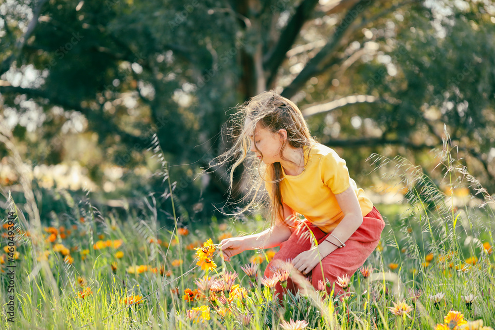 Portrait of pretty girl sitting in field with vibrant orange and yellow wildflowers Portrait of pretty girl sitting in field with vibrant orange and yellow wildflowers