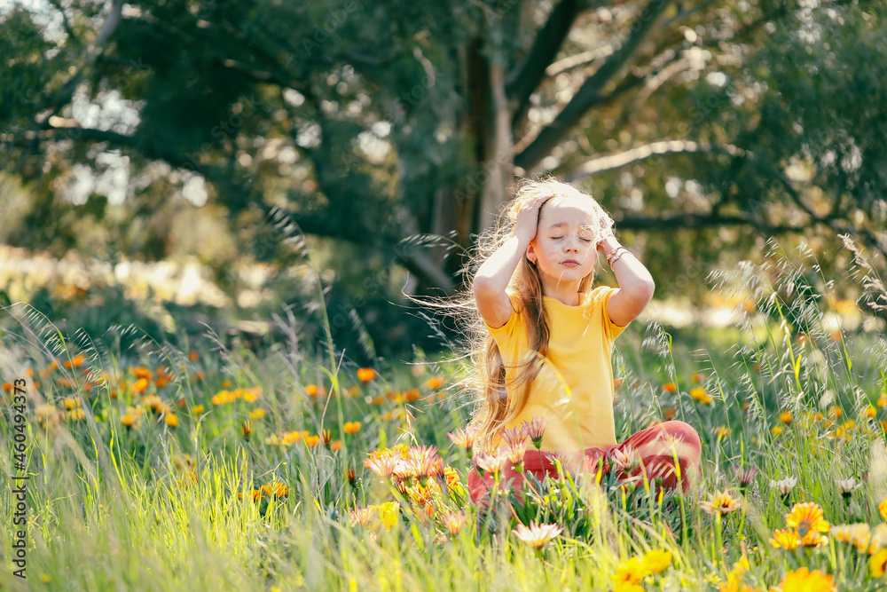 Portrait of pretty girl sitting in field with vibrant orange and yellow wildflowers Portrait of pretty girl sitting in field with vibrant orange and yellow wildflowers