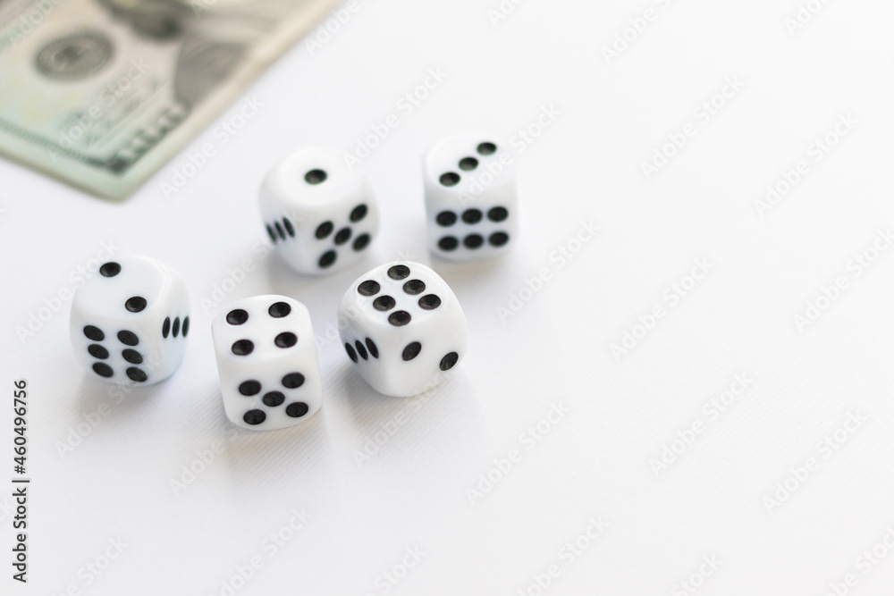 Dice and blurred 100 US dollar on white. Fortune, gaming addiction. Playing cube with numbers. Items for board games. Flat lay, top view, copy space. Dice and blurred 100 US dollar on white. Fortune, gaming addiction. Playing cube with numbers. Items for board games. Flat lay, top view, copy space.