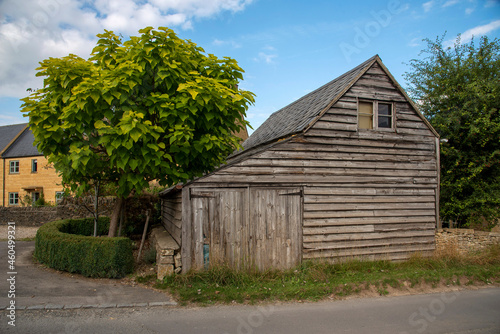 Guiting Power, Gloucestershire, England, UK. 2021. An old wooden barn with small garage doors in the rural Cotswolds village of Guiting Power.