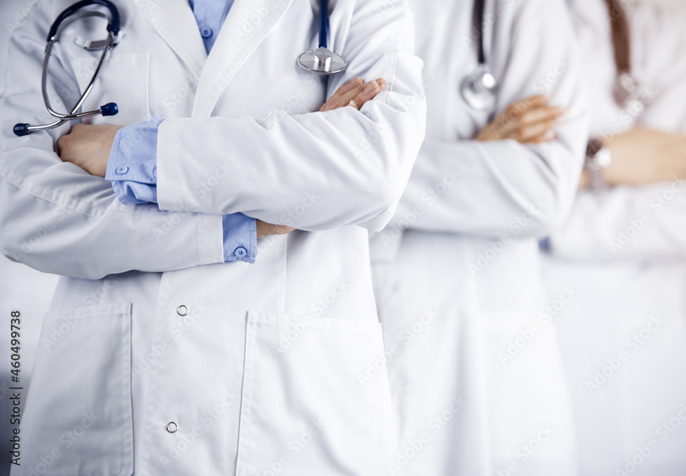 Group of modern doctors standing as a team with arms crossed in sunny hospital and ready to help patients. Medical help, insurance in health care Group of modern doctors standing as a team with arms crossed in sunny hospital and ready to help patients. Medical help, insurance in health care