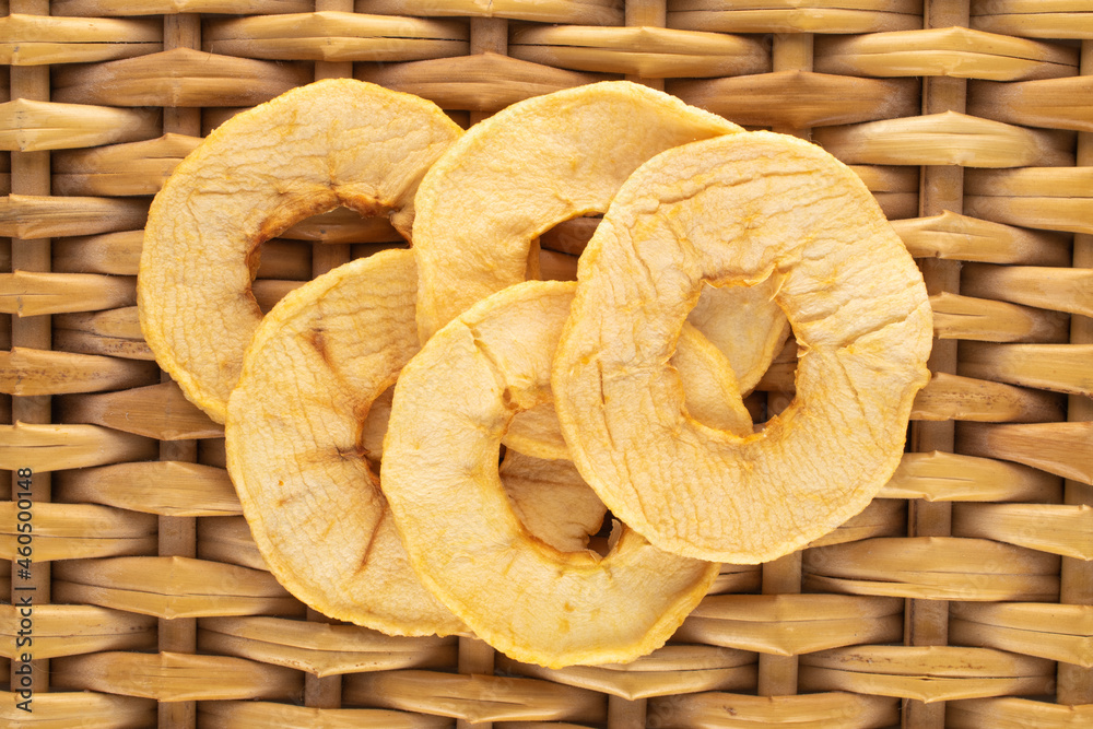 Several sweet crunchy, apple chips on a vine mat, close-up, top view.