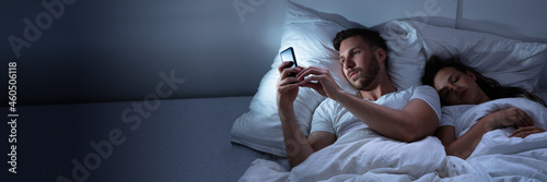 Man Using Cellphone While Her Wife Sitting On Bed