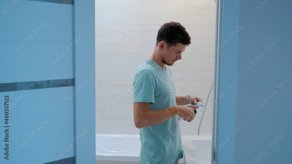 The man in the bathroom goes to the sink and starts brushing his teeth. Side view. Overall plan The man in the bathroom goes to the sink and starts brushing his teeth. Side view. Overall plan