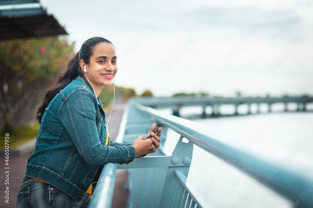 Latin woman looking very happy with the mobile in her hand and with headphones
