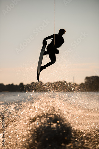 silhouette of wakeboarder jumping high making tricks in the air © fesenko