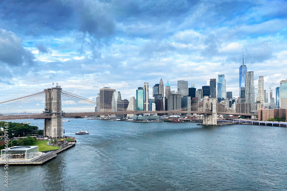 Brooklyn Bridge and Downtown Manhattan in New York City on a partially cloudy day.