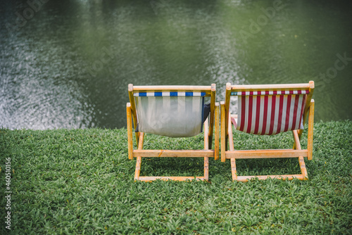 Two Deck chairs on lush green lawn with trees and in front of the river