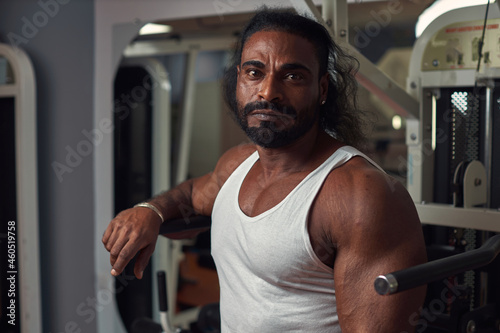 muscular sexy man with dark skin stands in the gym against the background of equipment. High quality photo