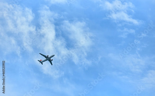 The plane flies in the evening blue sky with clouds