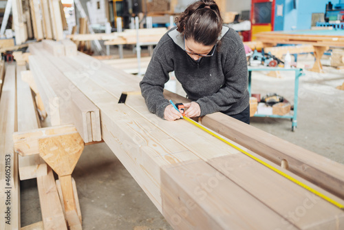 Female worker measuring a length of timber in a workshop