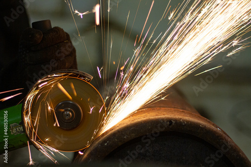 Spark grinder. Hot white sparks when cutting steel material. Industrial worker cutting metal with a grinder. Lots of glowing sparks