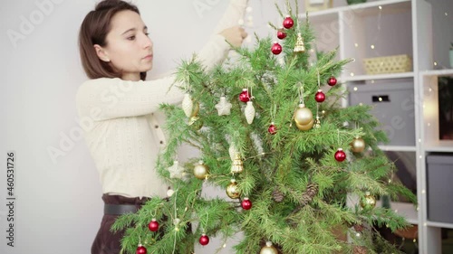Young woman decorates a Christmas tree with luminous garlands.Merry Christmas and Happy Holidays. The morning before Xmas. 