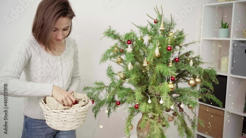 Young woman decorates a Christmas tree with luminous garlands.Merry Christmas and Happy Holidays. The morning before Xmas. 