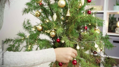 A young man decorates a Christmas tree vintage balls. Hands close-up. Merry Christmas and Happy Holidays. .The morning before Xmas. Banner with copy space.