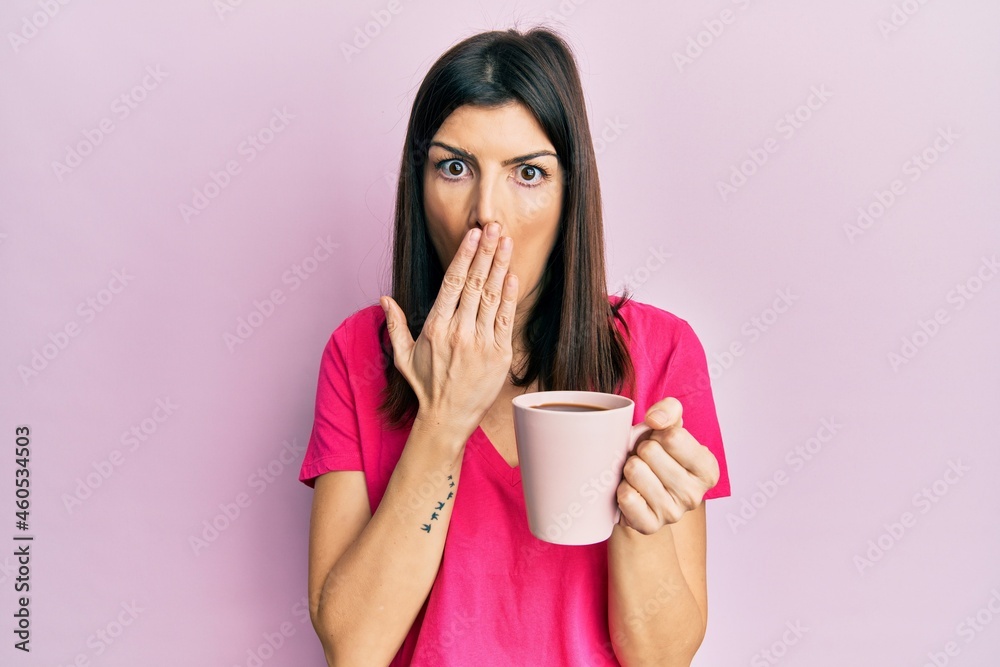Young hispanic woman drinking a cup of coffee with angry face, negative sign showing dislike with thumbs down, rejection concept Young hispanic woman drinking a cup of coffee with angry face, negative sign showing dislike with thumbs down, rejection concept