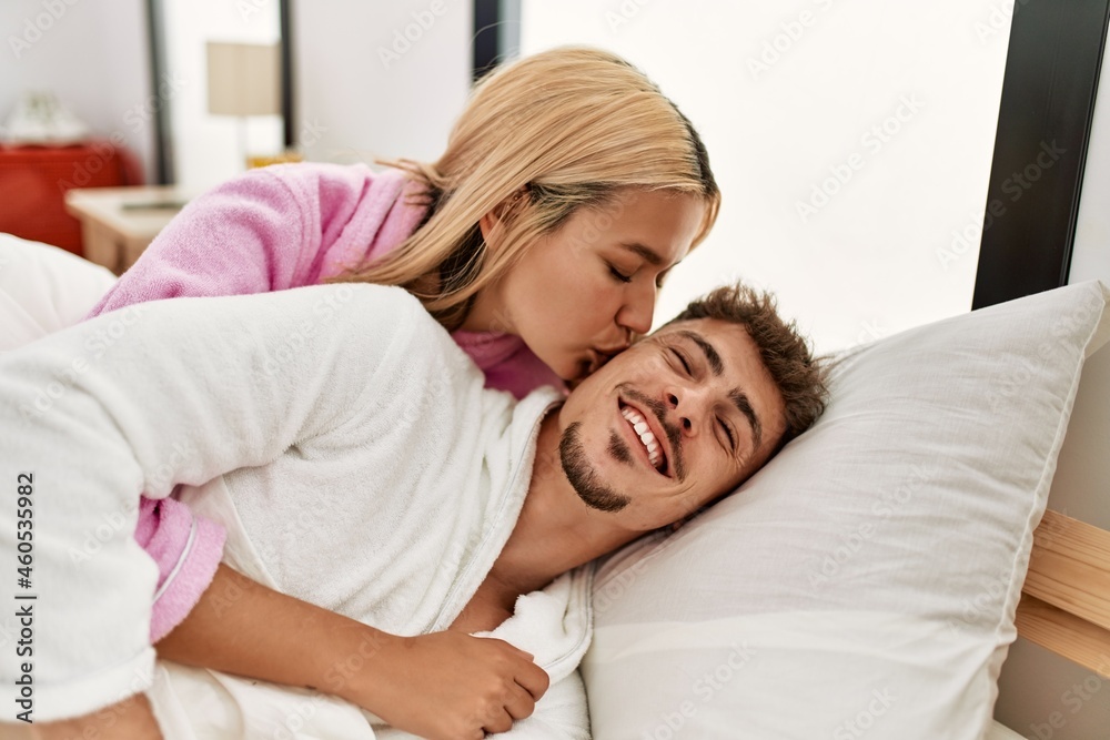 Young caucasian couple kissing and hugging lying on the bed at home. Young caucasian couple kissing and hugging lying on the bed at home.