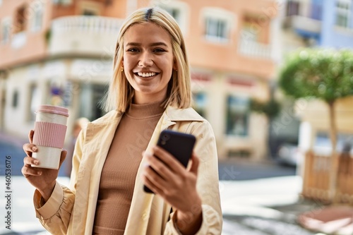 Young blonde girl using smartphone drinking coffee at the city.