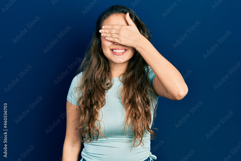 Young hispanic girl wearing casual clothes smiling and laughing with hand on face covering eyes for surprise. blind concept.