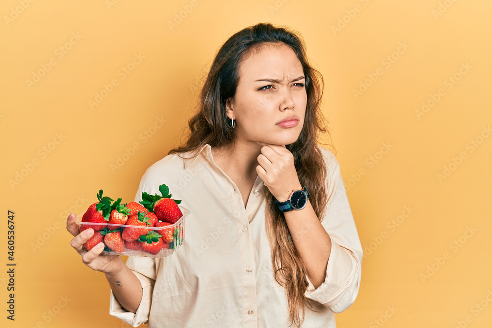Young hispanic girl holding strawberries touching painful neck, sore throat for flu, clod and infection Young hispanic girl holding strawberries touching painful neck, sore throat for flu, clod and infection