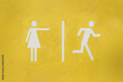 WC toilet sign with women pointing at men running away printed over yellow background, concept