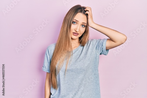 Young blonde girl wearing casual t shirt confuse and wonder about question. uncertain with doubt, thinking with hand on head. pensive concept.