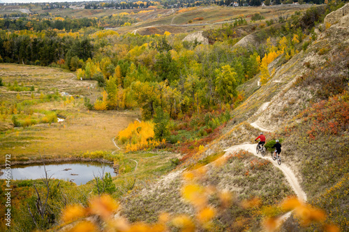 Two mountain bikers ride the Bowmont trail system in autumn colours above Dale Hodges Park in Calgary Alberta Canada