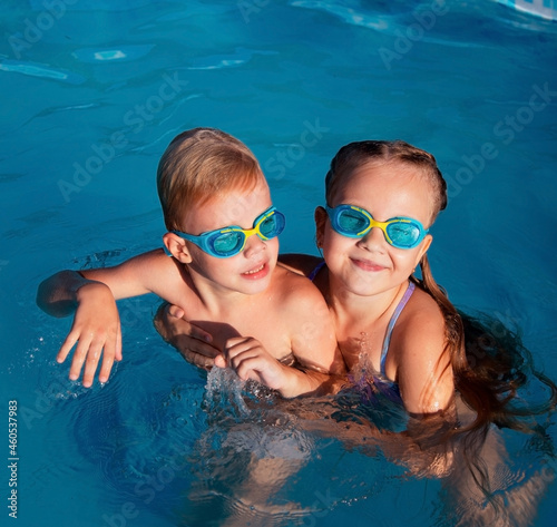 Cheerful family in swimming pool smiling at camera
