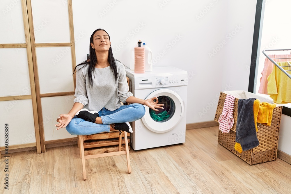 Young latin woman doing yoga waiting for washing machine at laundry room Young latin woman doing yoga waiting for washing machine at laundry room