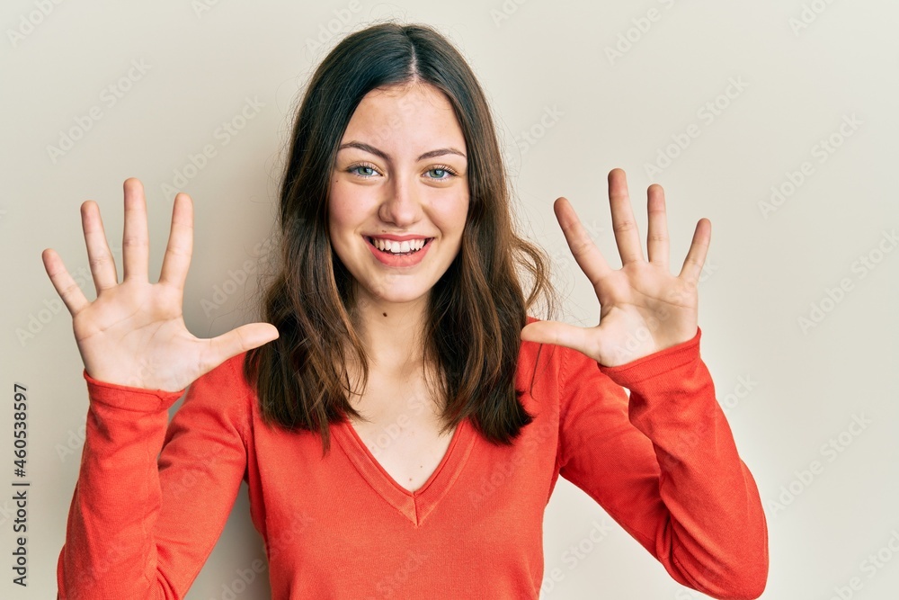 Young brunette woman wearing casual clothes showing and pointing up with fingers number ten while smiling confident and happy. Young brunette woman wearing casual clothes showing and pointing up with fingers number ten while smiling confident and happy.