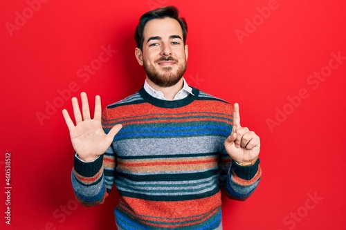 Handsome caucasian man with beard wearing elegant wool winter sweater showing and pointing up with fingers number six while smiling confident and happy.
