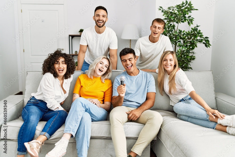 Group of young friends having party singing song using microphone at home. Group of young friends having party singing song using microphone at home.