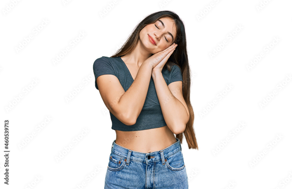 Young beautiful teen girl wearing casual crop top t shirt sleeping tired dreaming and posing with hands together while smiling with closed eyes. Young beautiful teen girl wearing casual crop top t shirt sleeping tired dreaming and posing with hands together while smiling with closed eyes.