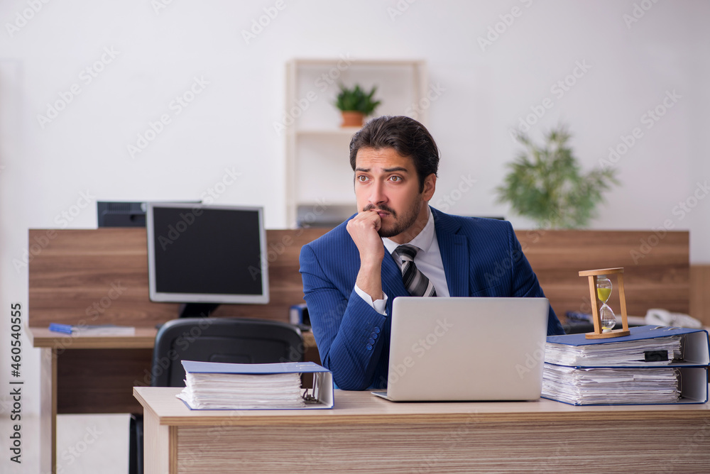 Young male employee in time management concept Young male employee in time management concept