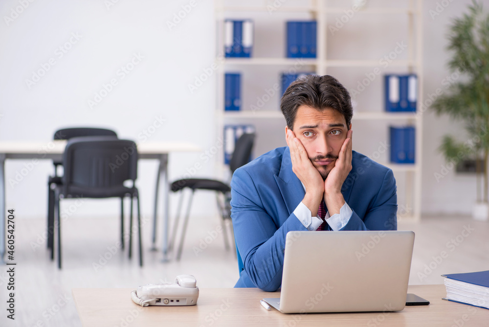 Young male employee unhappy with excessive work in the office Young male employee unhappy with excessive work in the office