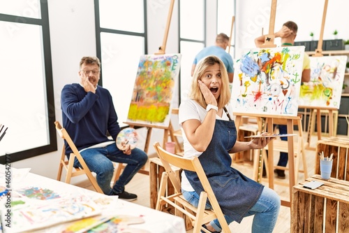 Group of middle age artist at art studio afraid and shocked, surprise and amazed expression with hands on face