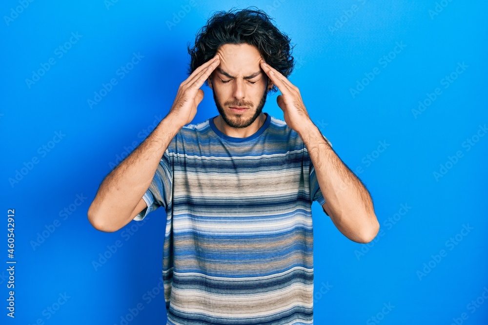 Handsome hispanic man wearing casual clothes over pink background with hand on head for pain in head because stress. suffering migraine. Handsome hispanic man wearing casual clothes over pink background with hand on head for pain in head because stress. suffering migraine.