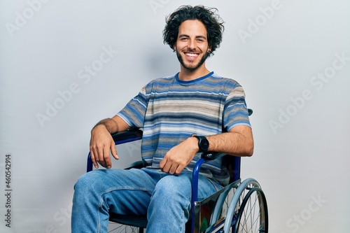 Handsome hispanic man sitting on wheelchair with a happy and cool smile on face. lucky person.