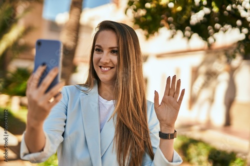 Young blonde businesswoman making video call using smartphone at the city.