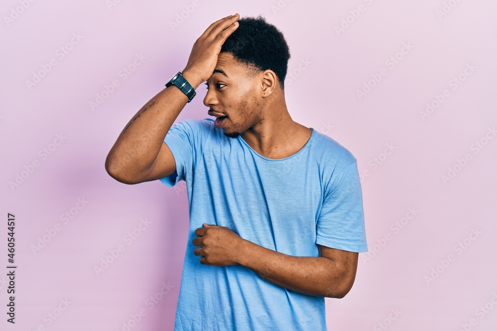 Young african american man wearing casual blue t shirt surprised with hand on head for mistake, remember error. forgot, bad memory concept. Young african american man wearing casual blue t shirt surprised with hand on head for mistake, remember error. forgot, bad memory concept.