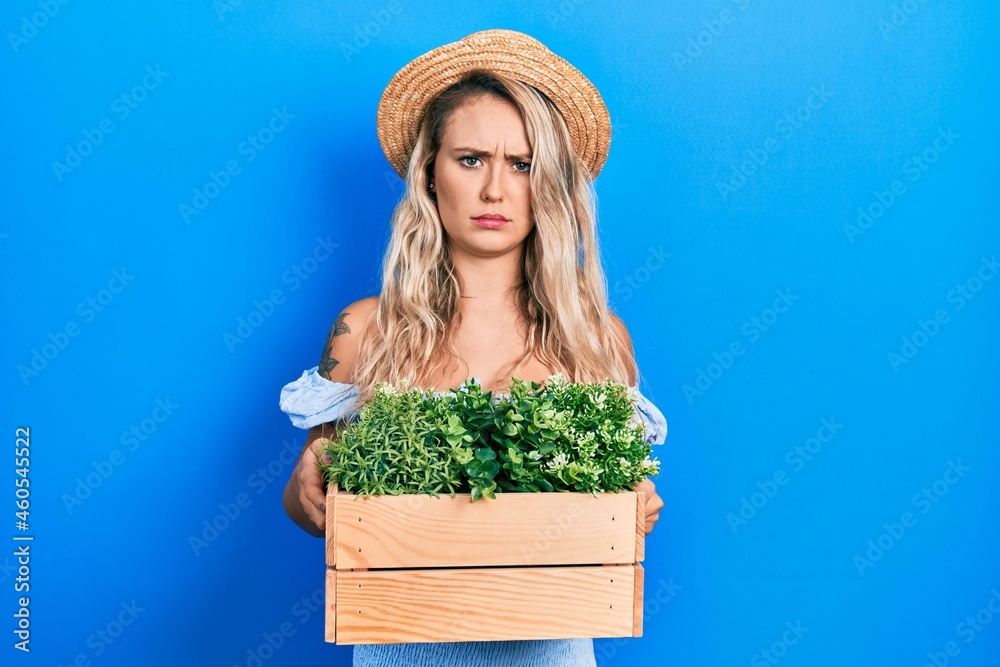 Beautiful young blonde woman holding wooden plant pot skeptic and nervous, frowning upset because of problem. negative person.