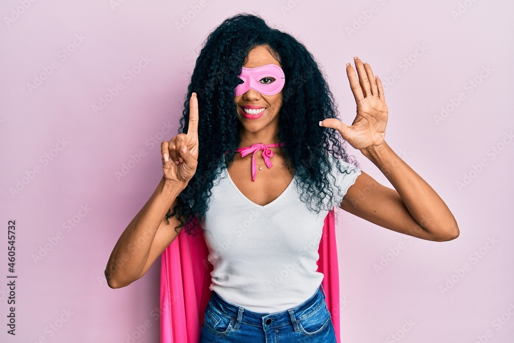 Middle age african american woman wearing super hero costume showing and pointing up with fingers number six while smiling confident and happy. Middle age african american woman wearing super hero costume showing and pointing up with fingers number six while smiling confident and happy.