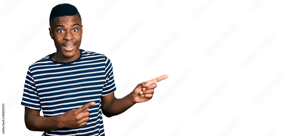 Young african american man pointing with fingers to the side celebrating crazy and amazed for success with open eyes screaming excited. Young african american man pointing with fingers to the side celebrating crazy and amazed for success with open eyes screaming excited.